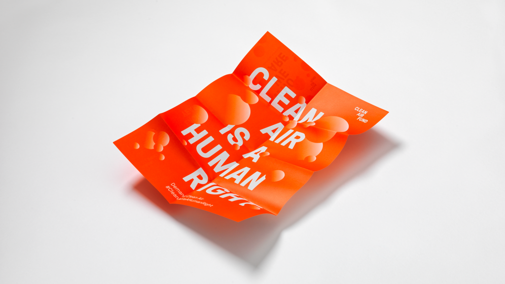 A folded poster reading "CLEAN AIR IS A HUMAN RIGHT" in bold, white text on an orange background.