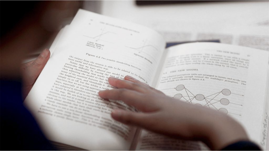 Photograph of a young person reading a physics book.