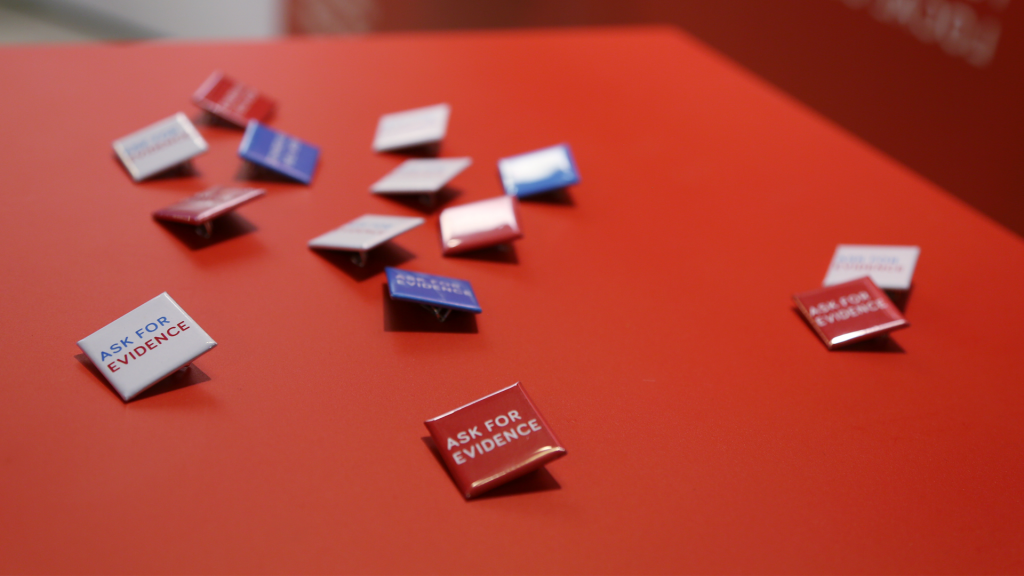 Pins from the Evidence Week event, reading "ASK FOR EVIDENCE" in white, red and blue versions.